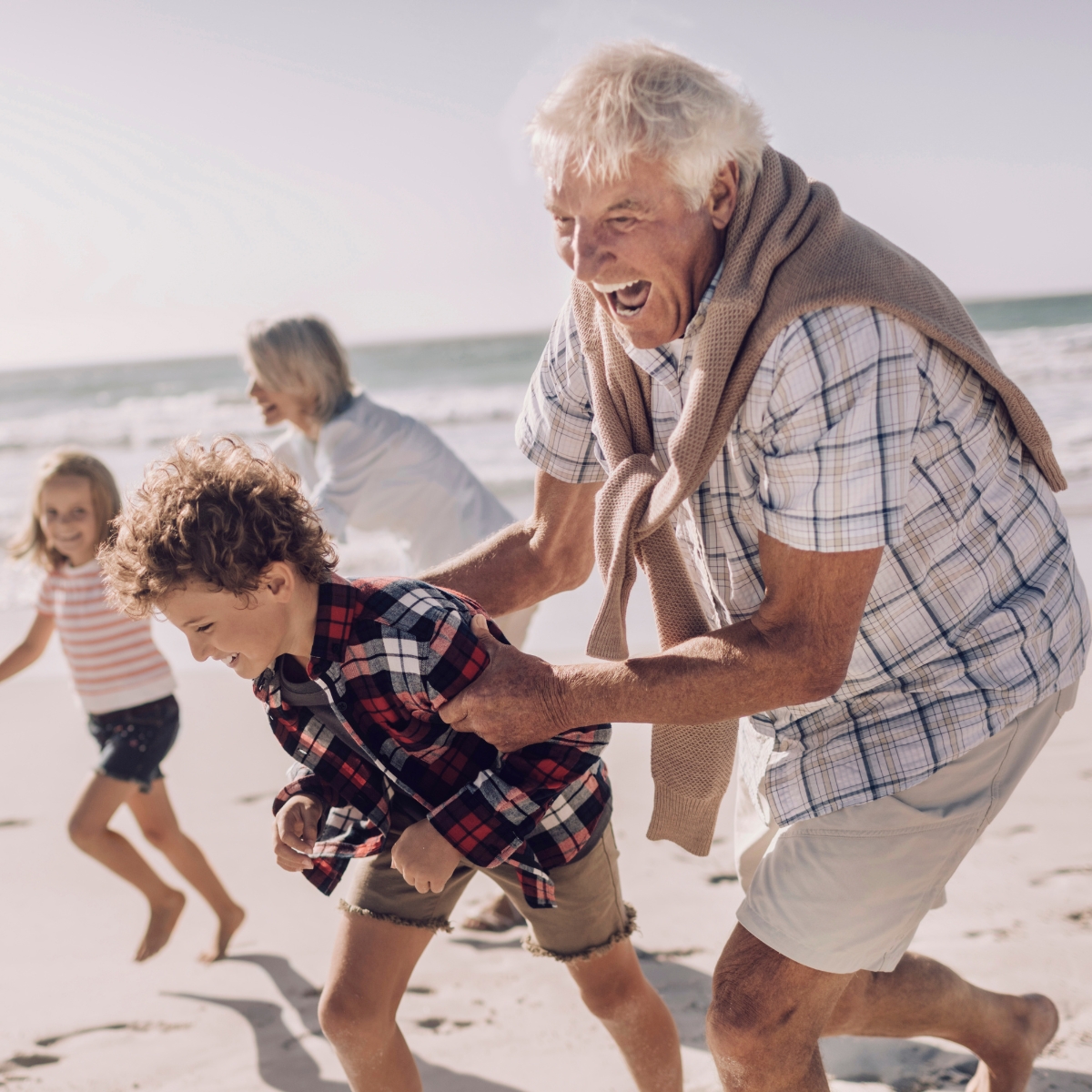 Grandparents chasing their grandchildren on a beach