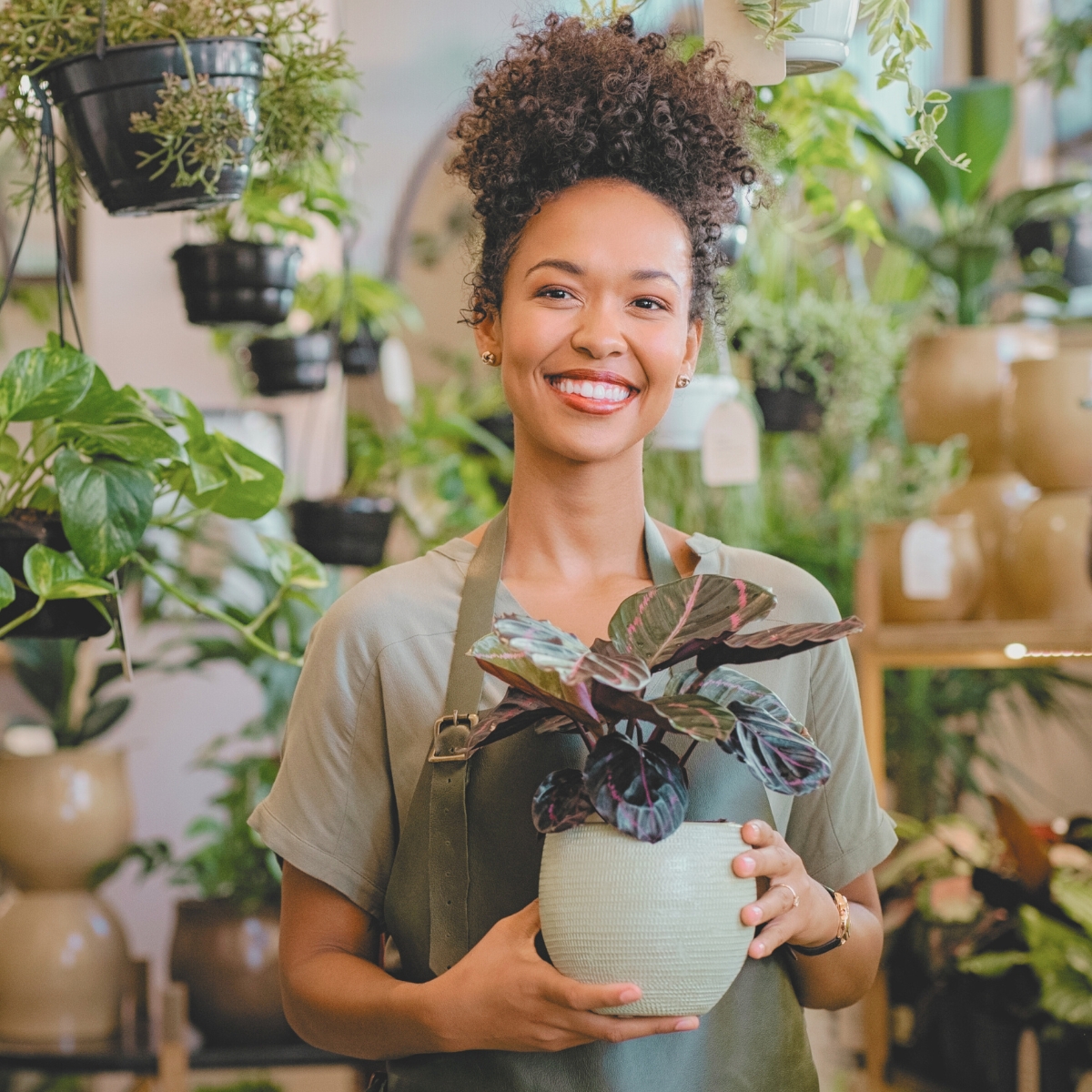 African-American business owner holding one of her products, a plant.